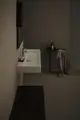 Weißer Waschtisch von Ideal Standard, wandhängend, rechteckige Form, mit Seifenschale und Wasserhahn, daneben ein Tischchen mit kosmetischen Produkten und einem Handtuch.